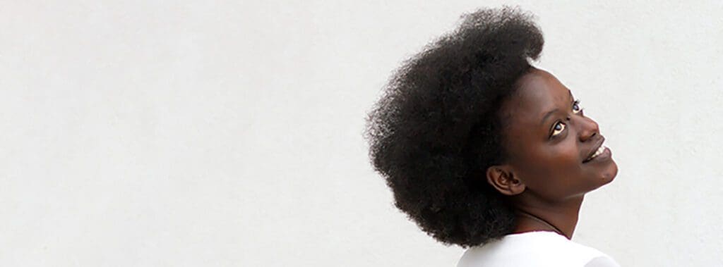 Side profile of a person with a large Afro hairstyle against a plain background.