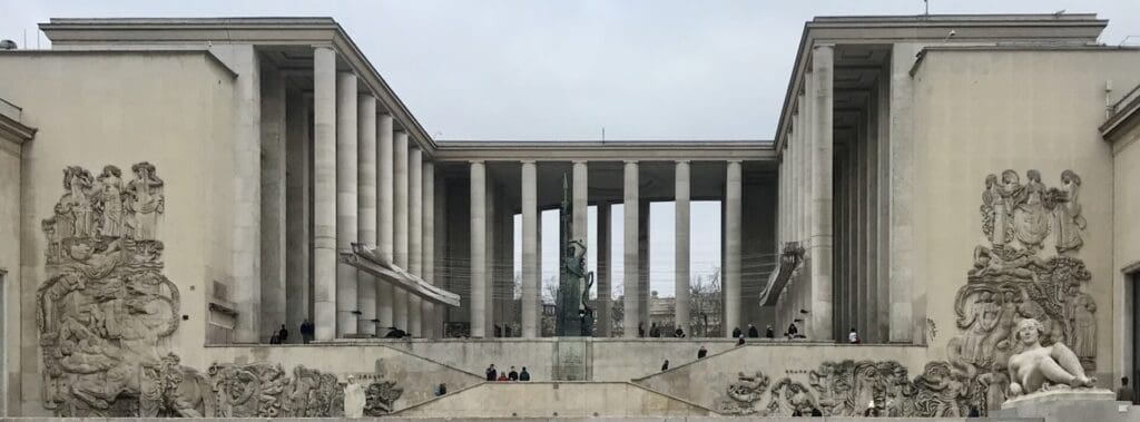 Modern building with tall columns and people sitting below.