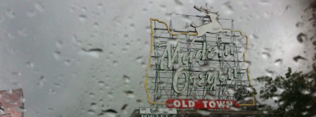 Vintage neon sign for "World's Only" with raindrops on glass.